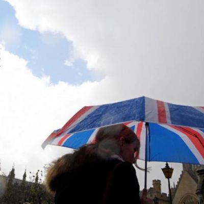 A woman carries a British union flag design umbrella as she walks past the Houses of Parliament in London, Britain