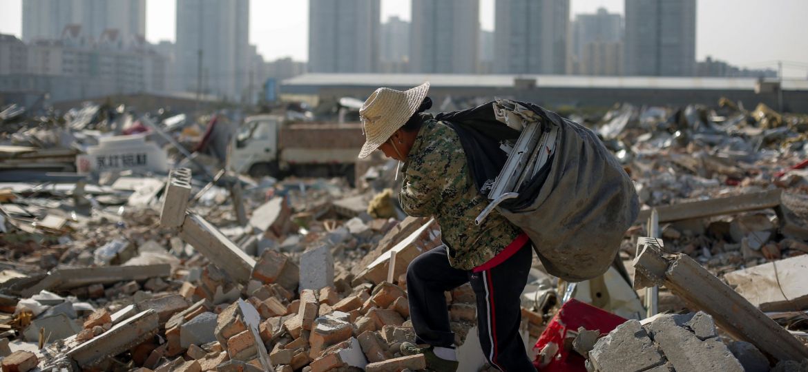 Migrant worker Wang Jun carries scrap material she collected from debris of demolished buildings at the outskirts of Beijing