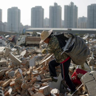 Migrant worker Wang Jun carries scrap material she collected from debris of demolished buildings at the outskirts of Beijing